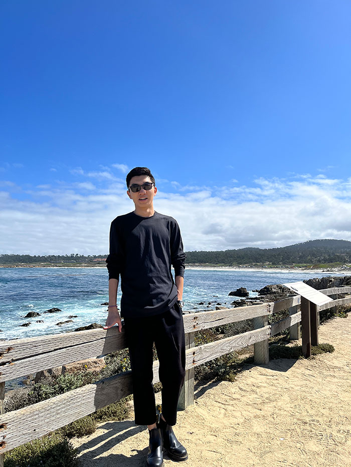 Keyang Pan leans against a railing overlooking the Pacific ocean