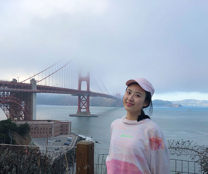 Vera Guo standing in front of foggy Golden Gate Bridge