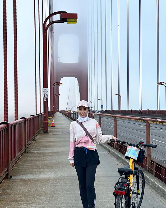 Vera Guo on the Golden Gate Bridge next to a bicycle