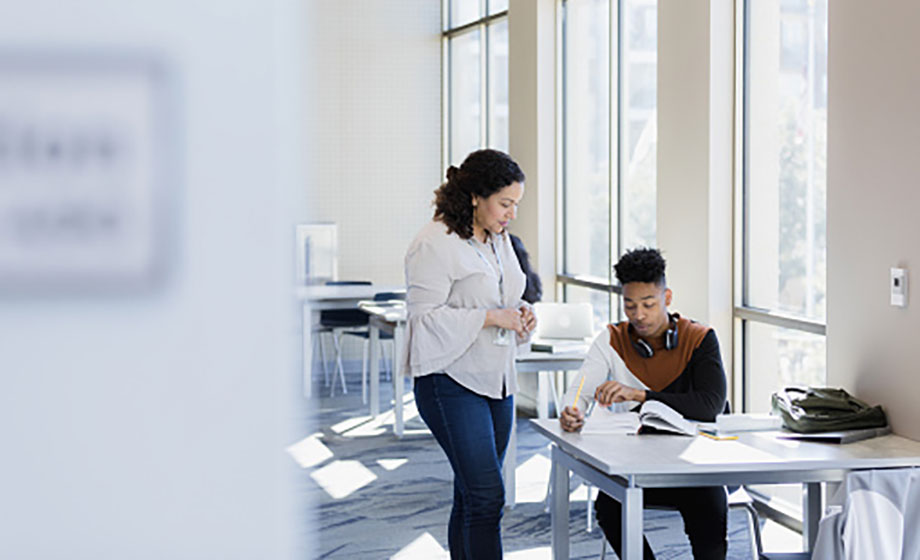 Older female high school counselor working with male high school student