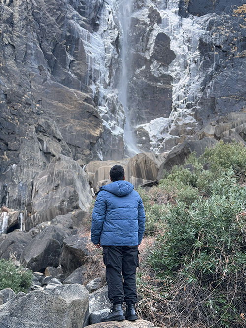 Tashrique Ahmed standing in front of a waterfall