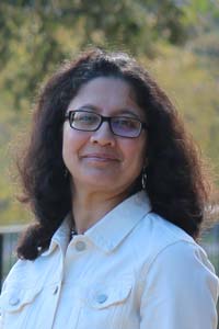 Madhura Limaye wearing a white collared shirt and glasses, outdoors