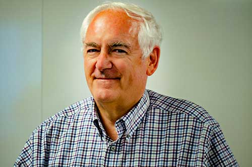 Panelist Tom Kendrick wearing a checkered shirt in front of a white wall