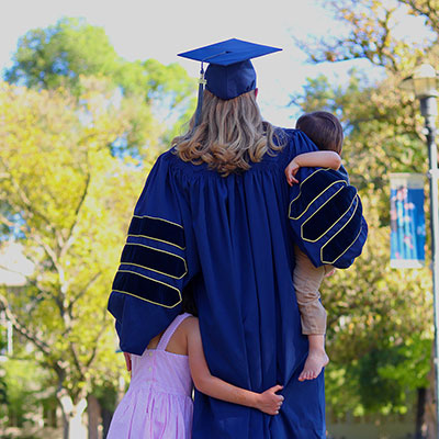 Photo of Anne Chiruvolu's back in graduation gown with her two children