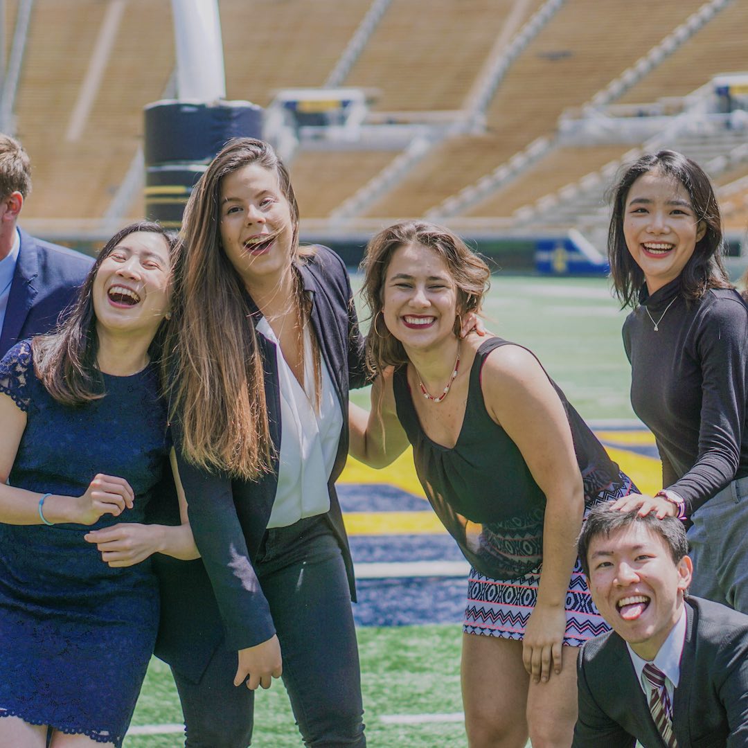 Karin and some of her friends laughing while taking a pic on the football field, in business professional attire. 