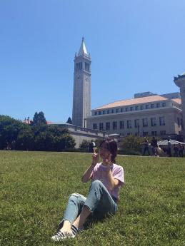 Xinyue yang sitting on the UC Berkeley campus with the campanile in background. Photo.
