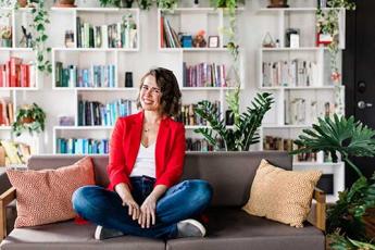 Photo of Jen Brown sitting on a couch in front of a book shelf