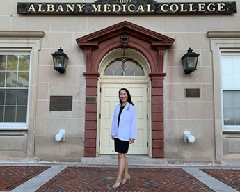 Post-Bacc Health alumna Charlotte Young in white jacket in front of building at Albany Medical College