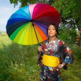 Sandra Titre in Asian-inspired dress holding a multi-colored umbrella