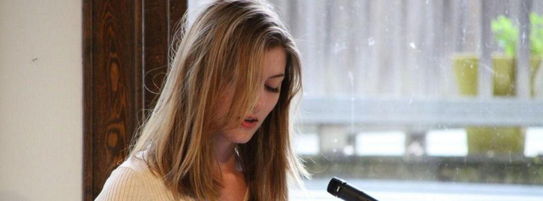 Professional Writing Community Impact Scholarship winner Adelle Brunstad reading her work at an event. Photo.