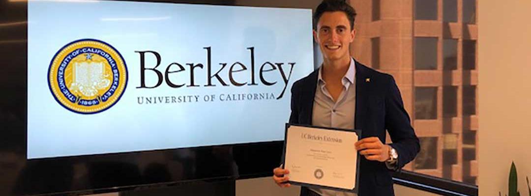 Photo of Alejandro Ruiz holding certificate of completion in front of a TV screen with Berkeley logo
