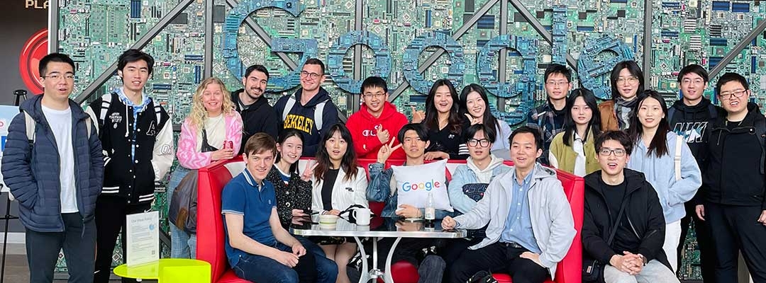 Group of international students sitting at a table in front of Google mosaic