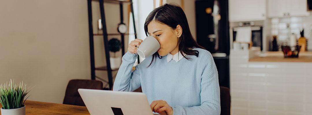 Stock photo of woman working from home and drinking coffee