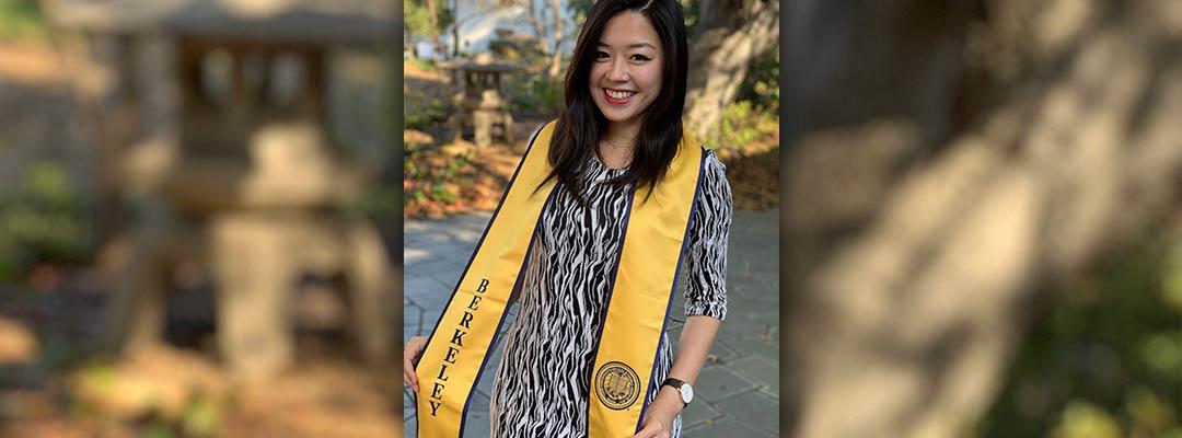 Jolin Wu wearing a Berkeley graduation scarf standing in front of some trees