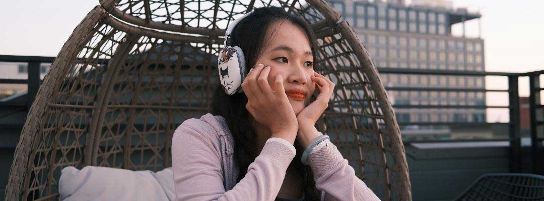 Photo of Lydia Bao wearing headphones while sitting in a rattan chair