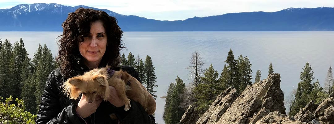 Marianna Lenoci posing in front of a Sierra lake while holding her puppy