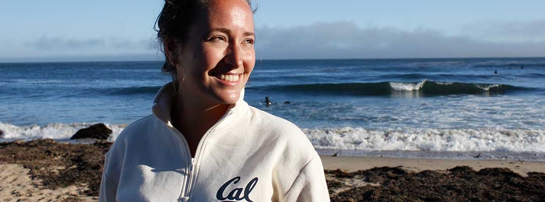 Photo of Nicole Schreyer at the beach wearing a white UC Berkeley sweatshirt