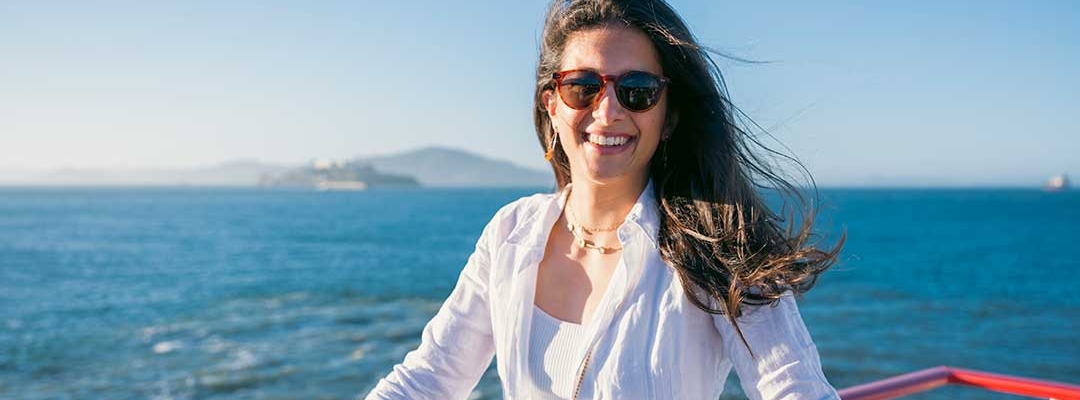 Photo of Perline Hochart wearing all white clothes while on a sailboat on the San Francisco Bay