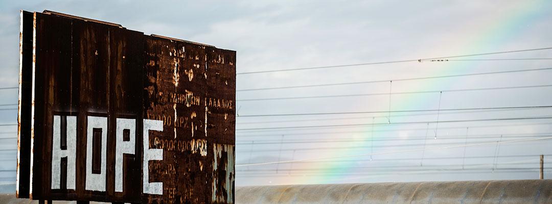 Stock photo of Greek refugee center with "hope" graffiti and rainbow