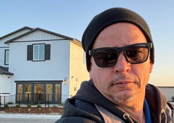 Selfie of Juan Resendes standing in front of a house