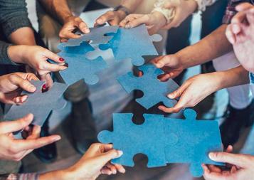 Group of diverse professionals holding jigsaw puzzle pieces
