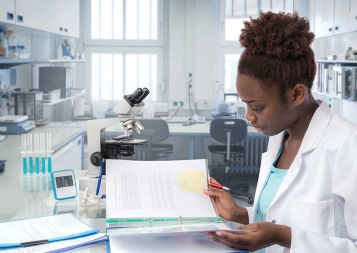 Black young female professional reading a manual in a science lab