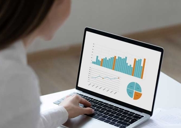 Woman working on laptop displaying business graphs