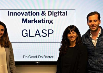 Custom programs students standing in front of digital display of their GLASP marketing presentation