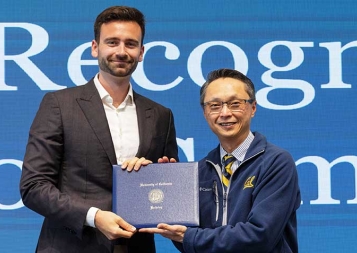 Lucas Mortier on left with Henry Tsang standing in front of blue background accepting a diploma