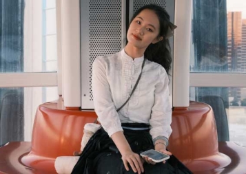 Lydia Bao sitting on an orange round couch in front of windows