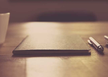 Image of closed notebook and pen on wooden table