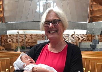 Photograph of Alcohol and Drug Abuse Studies graduate Therese Becker holding her grandson at his baptism