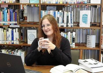 Editing student, scholarship winner Tracy Locken at a table in the library, with a laptop and books