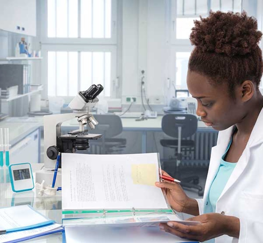 Black young female professional reading a manual in a science lab