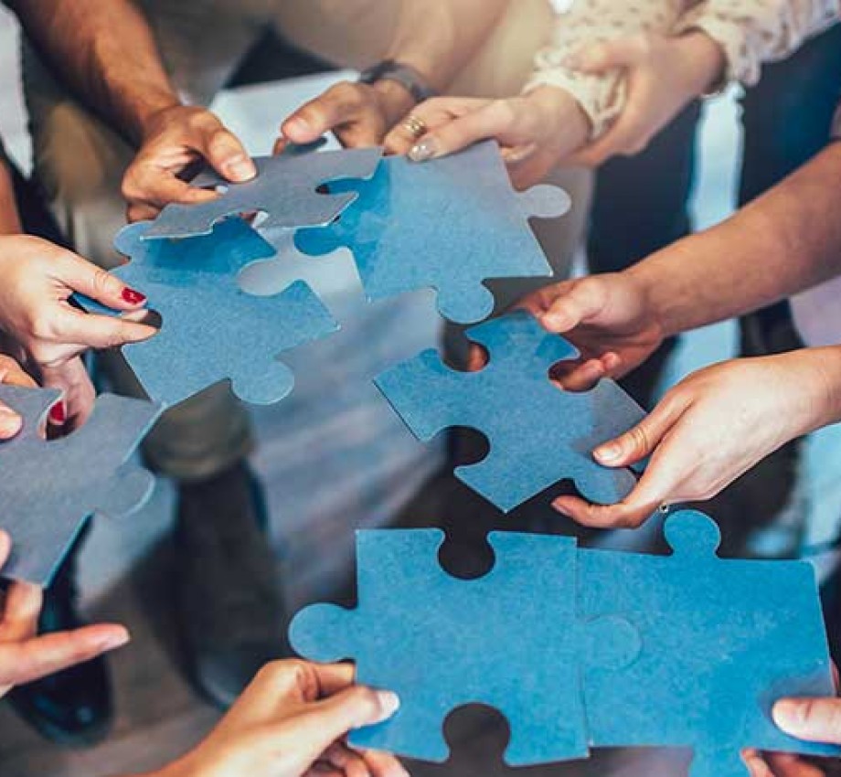 Multicultural employees putting together oversized jigsaw puzzle pieces