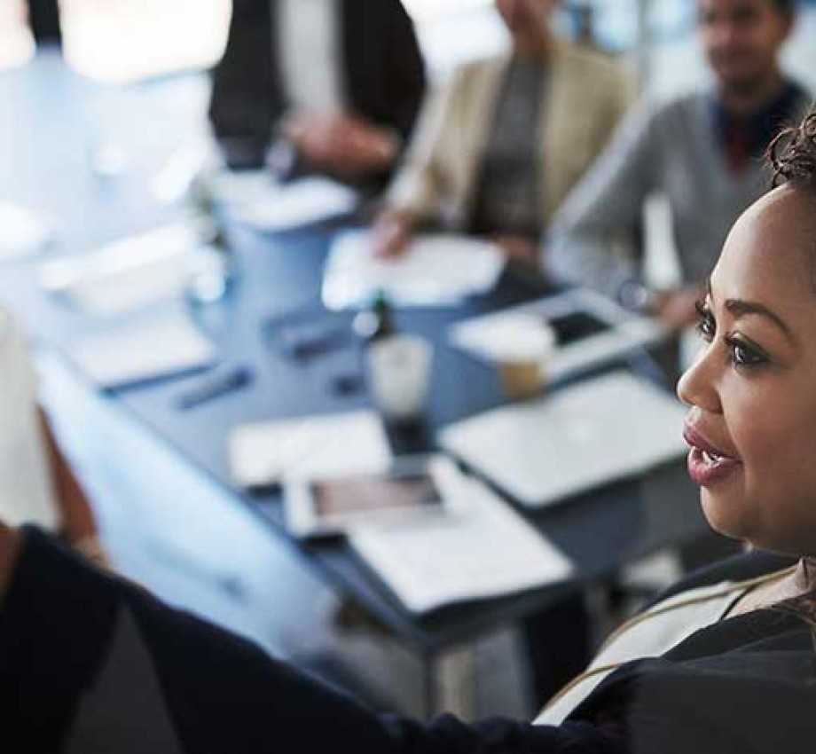 Black woman professional leading meeting while drawing on a white board