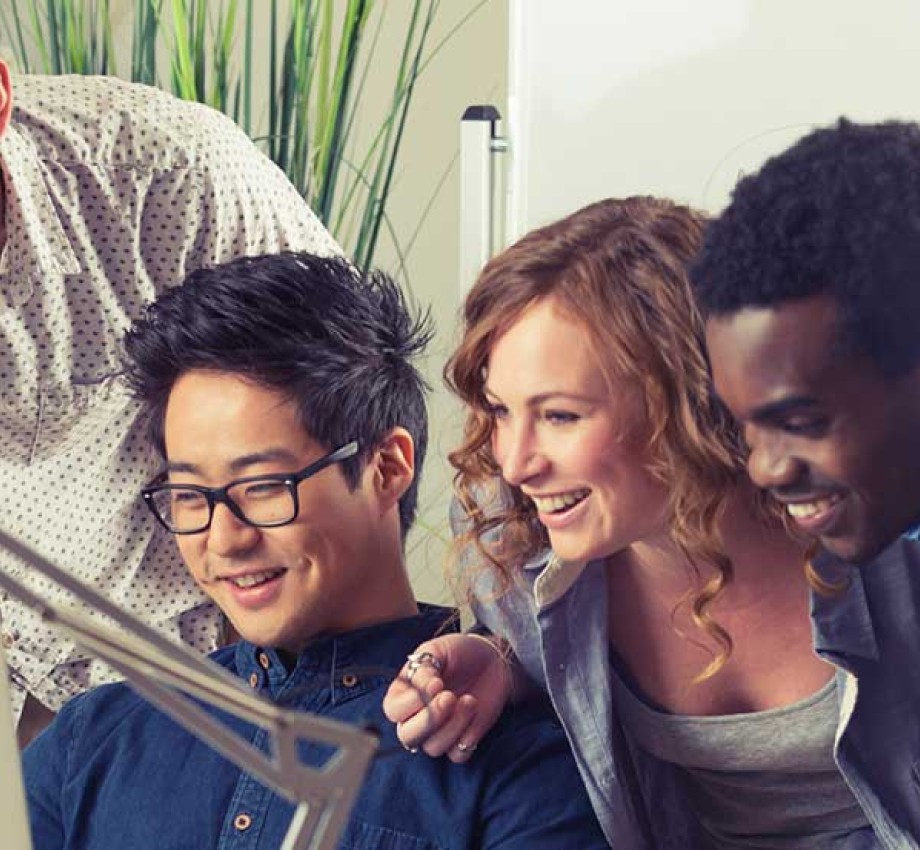 Photo of four diverse young professionals looking at a computer screen