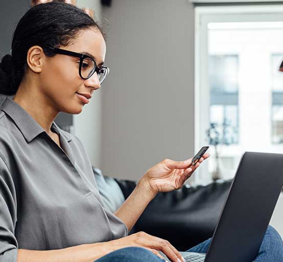 Photo of woman sitting on couch while working on a laptop