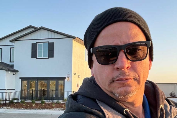 Selfie of Juan Resendes standing in front of a house