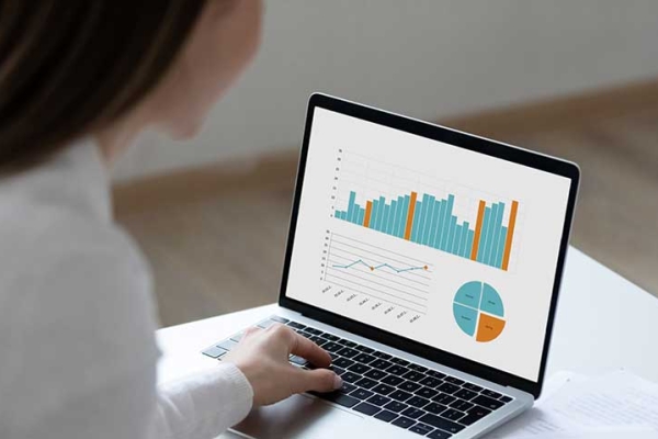 Woman working on laptop displaying business graphs