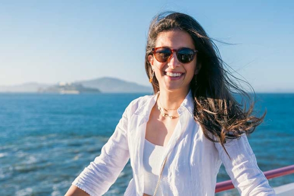 Photo of Perline Hochart wearing all white clothes while on a sailboat on the San Francisco Bay