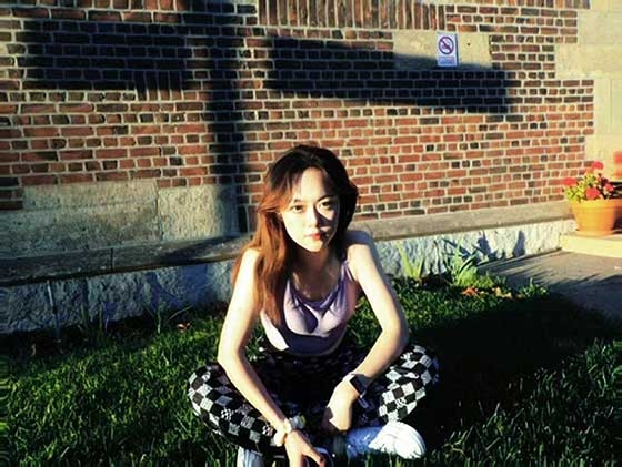 Lucy Zhang sitting on the grass outside of a brick building