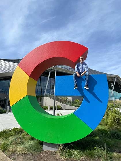 Sebastian Sartor sitting on top of a tall Google sign