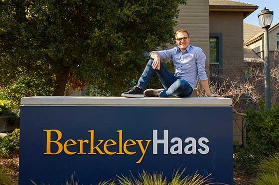 Sebastian Sartor sitting on top of the Berkeley Haas sign