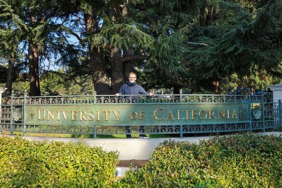 Sebastian Sartor standing behind the University of California sign