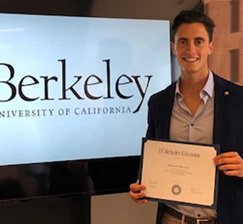 Photo of Alejandro Ruiz holding certificate of completion in front of a TV screen with Berkeley logo