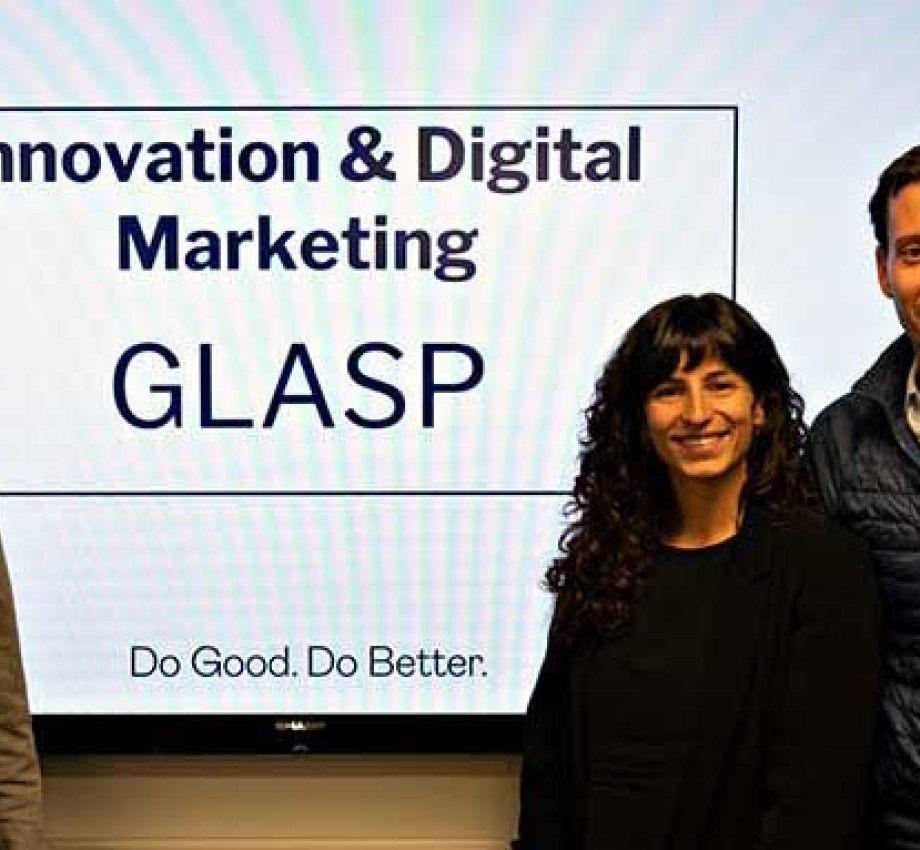 Custom programs students standing in front of digital display of their GLASP marketing presentation