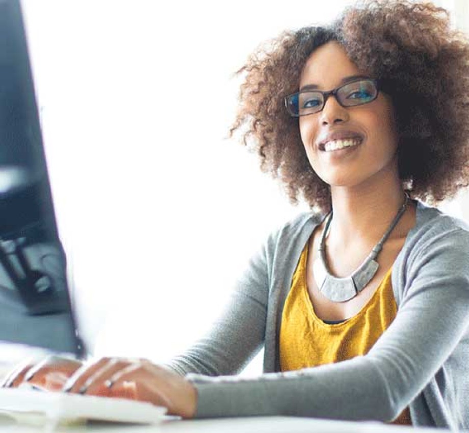 young professional typing on a computer keyboard looking at camera