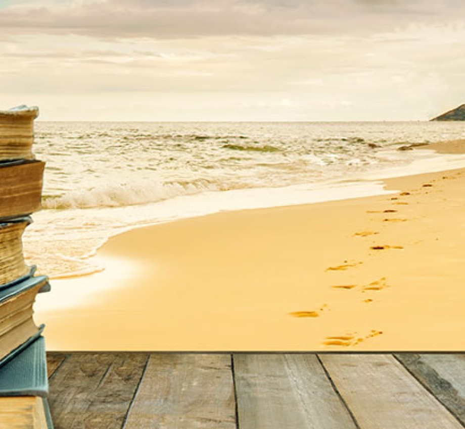 stock photo of a stack of books on a woden table by the beach