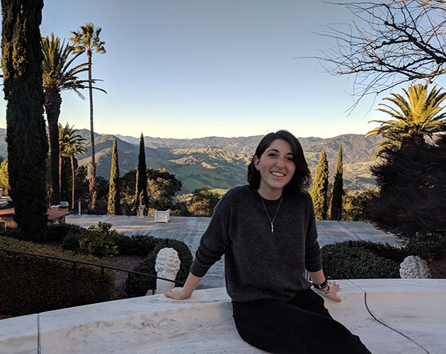 Photo of Emilie Biondi sitting on a granite stair with beautiful landscape behind